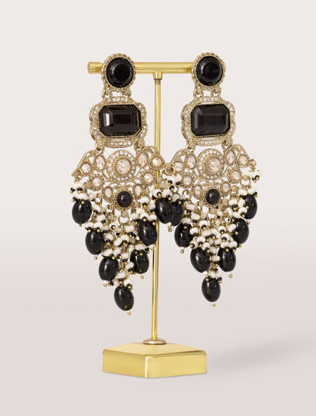 black and gold earrings on a stand against a light background