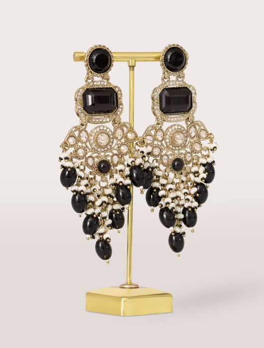 black and gold earrings on a stand against a light background
